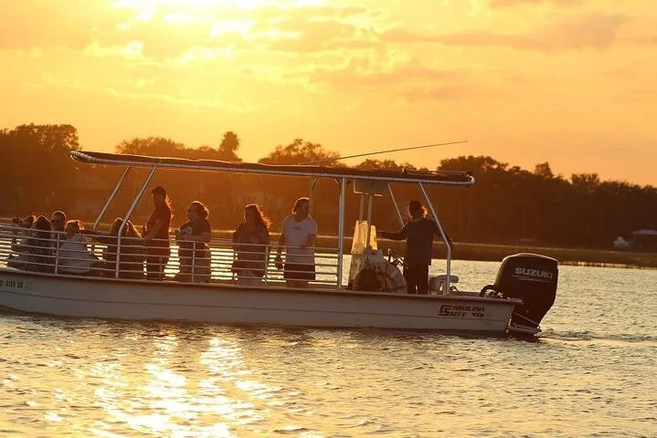 Passengers on a boat tour during a beautiful sunset over the water.